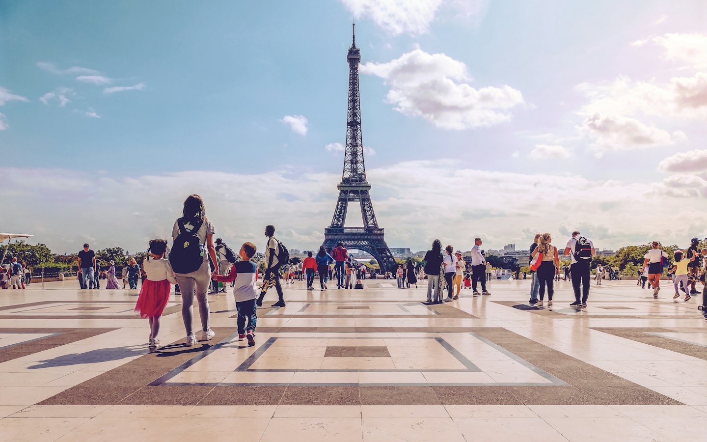 Family walks across the plaza towards the Eiffel Tower.