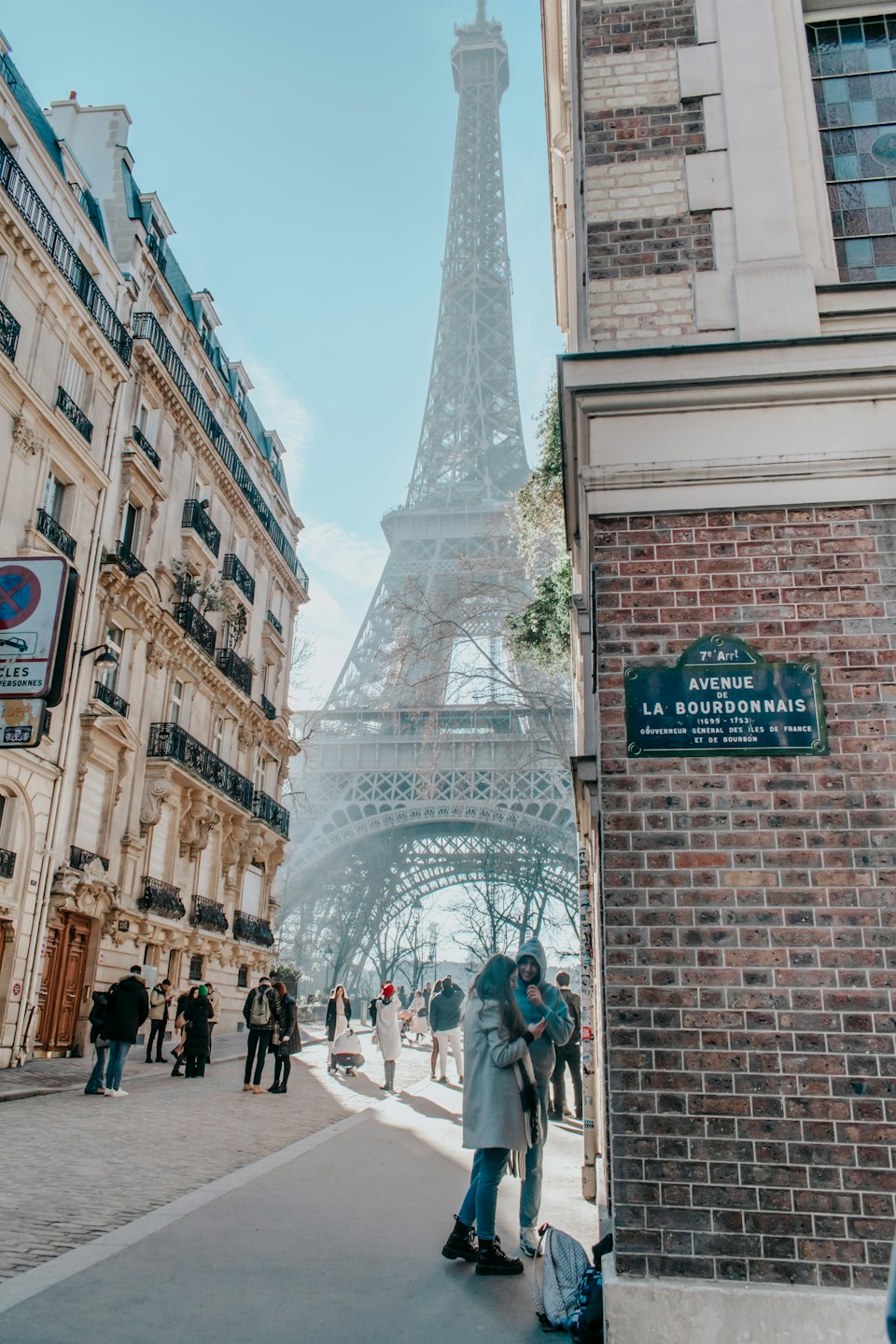 People walk and talk on a Parisian street near the Eiffel Tower.
