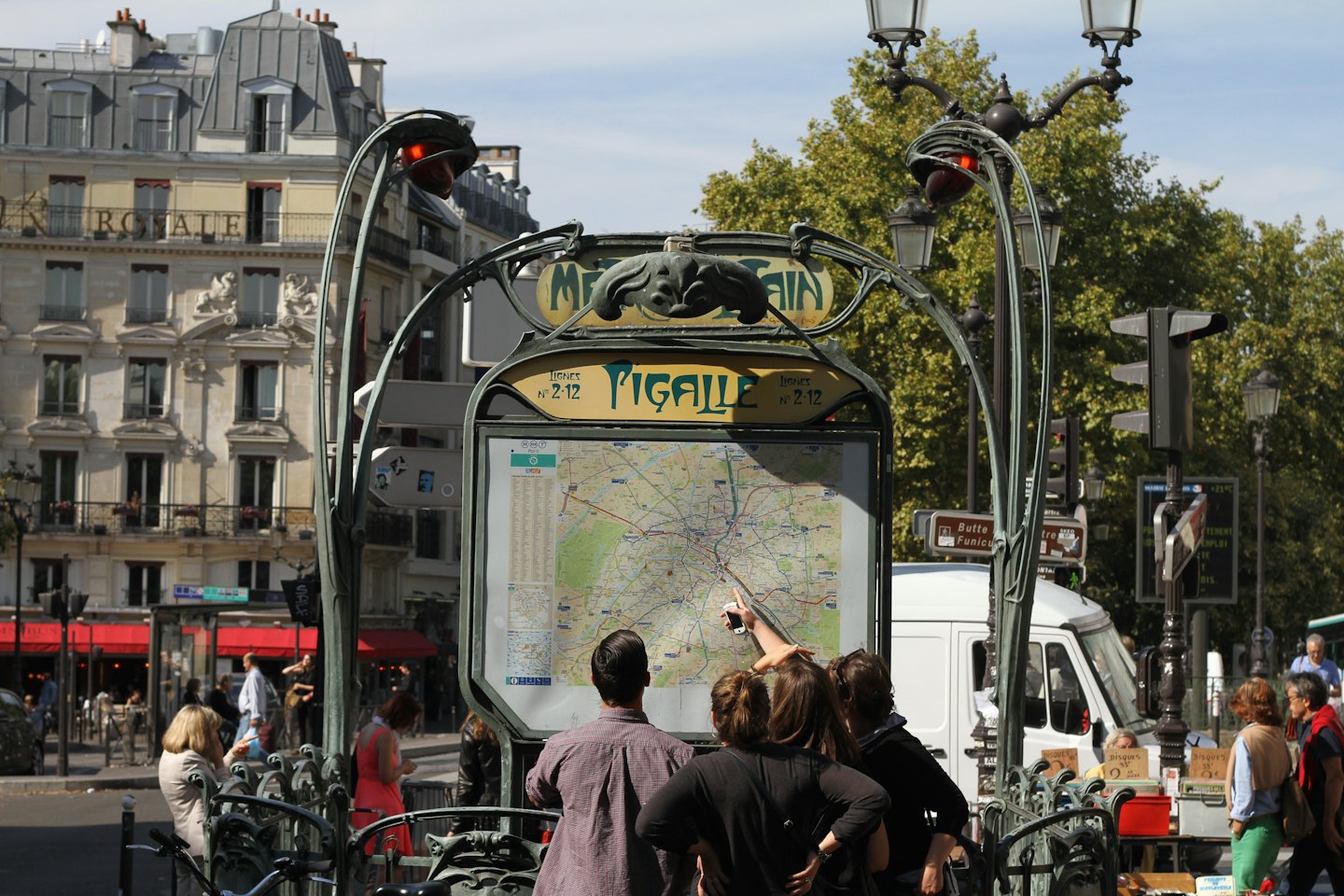 People gathered around a Paris Metro sign looking at a map.