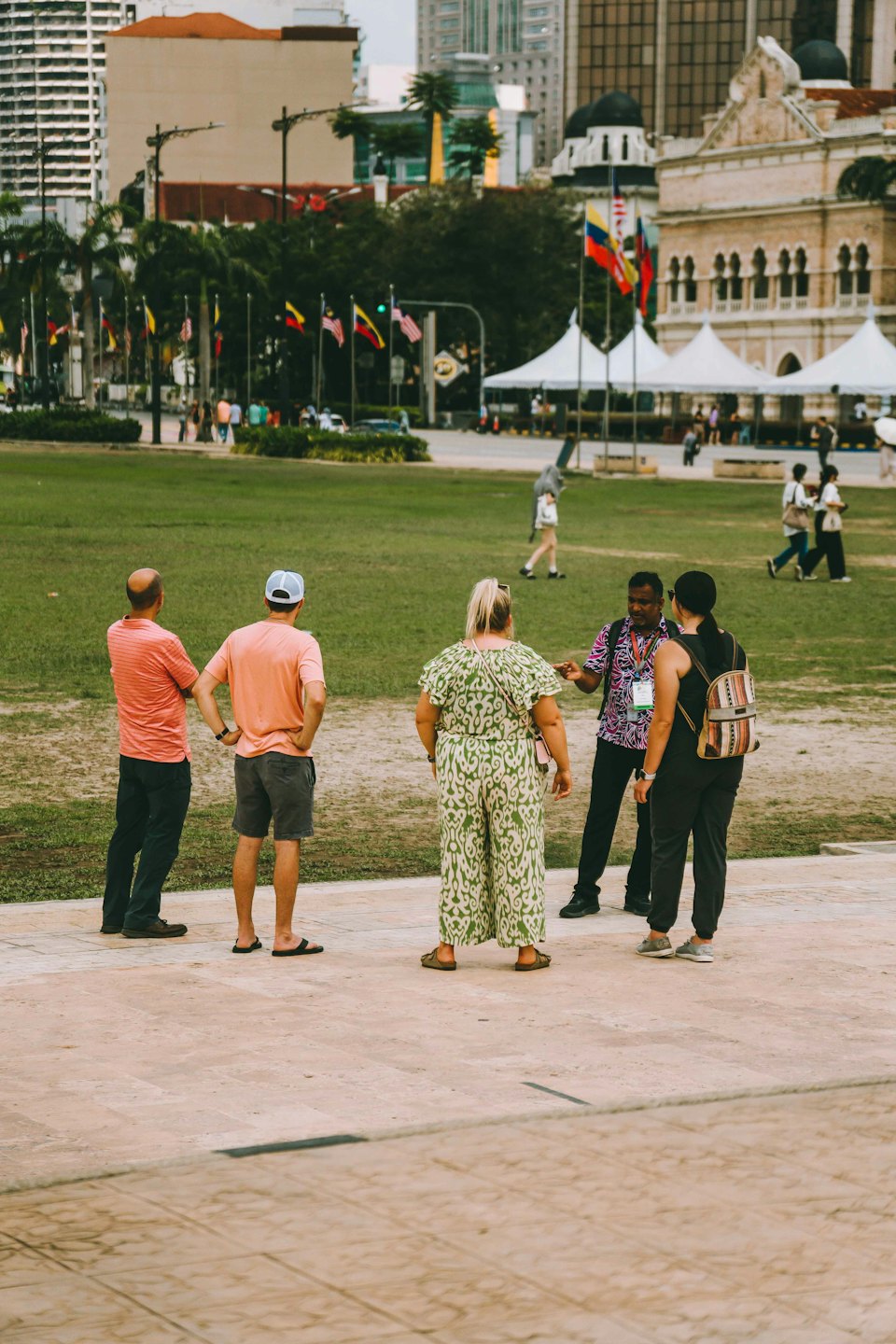 A tour guide speaks to a group of tourists in a park.